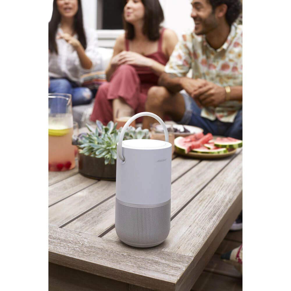 White portable speaker on a wooden table with people in the background