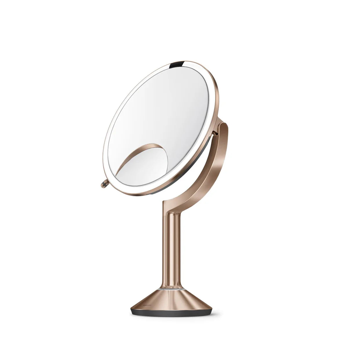This image shows a side view of the Simplehuman makeup mirror with a rose gold finish. The mirror is tilted slightly, showcasing its adjustable angle feature, which allows the user to find the perfect position for their grooming or makeup application. The design includes a circular mirror with an LED light ring that provides bright, even lighting, ideal for detailed tasks. The mirror is mounted on a sleek, slender stand that complements its overall modern and elegant aesthetic. The base of the mirror is st