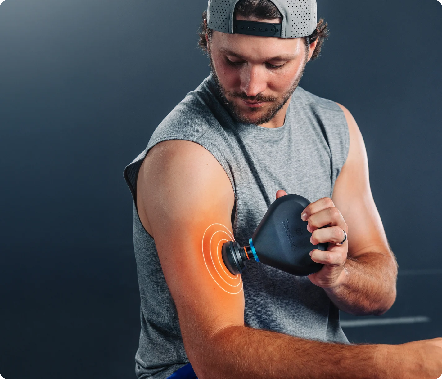 Person using Therabody Theragun Mini Plus heated massage gun on shoulder for muscle recovery