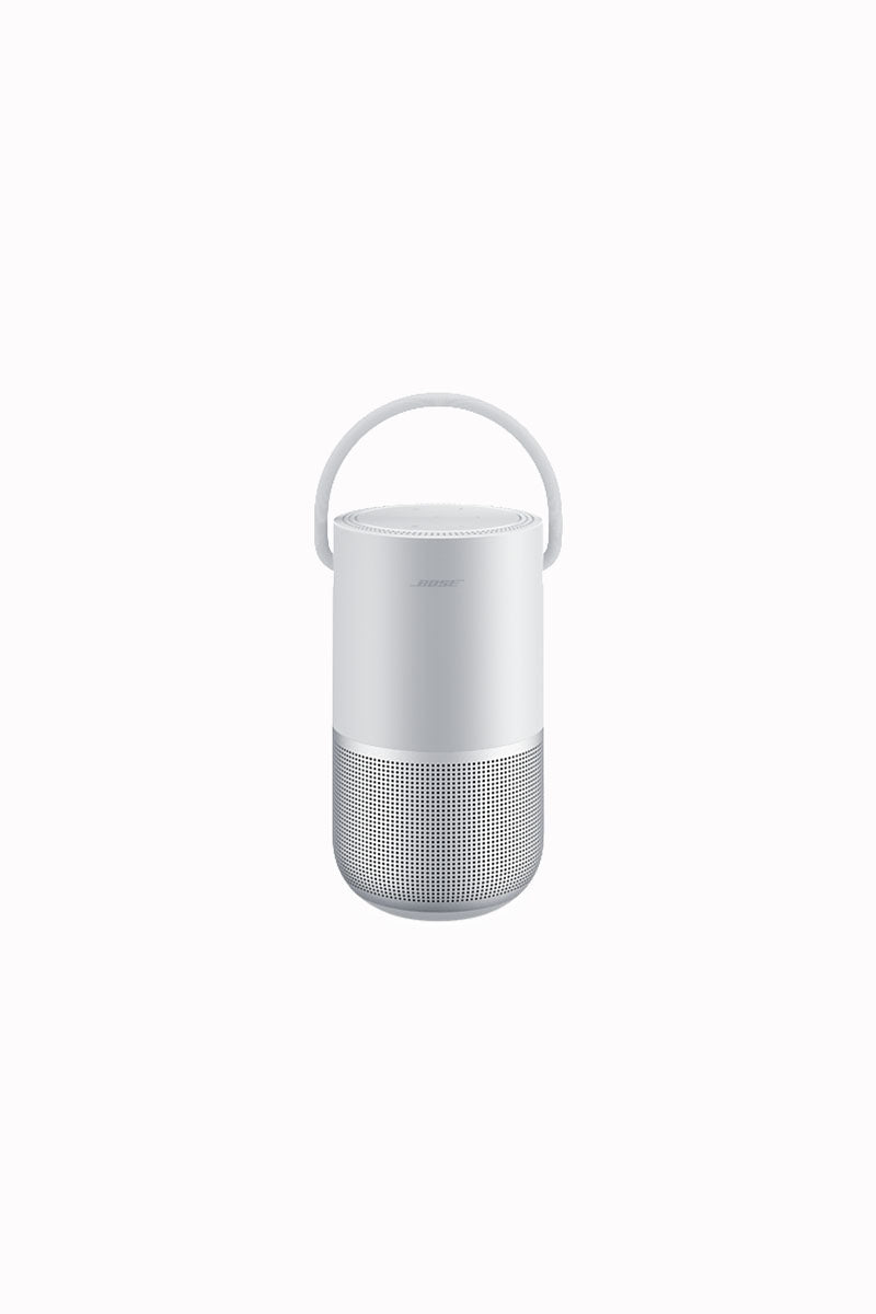 This image displays a compact white Bose portable speaker with a handle for easy carrying. The speaker has a cylindrical design, with a mesh grille at the lower section that enhances sound output. Its sleek, minimalistic look reflects the high-end, modern design typical of Bose products, combining aesthetics with practical functionality for on-the-go audio solutions.