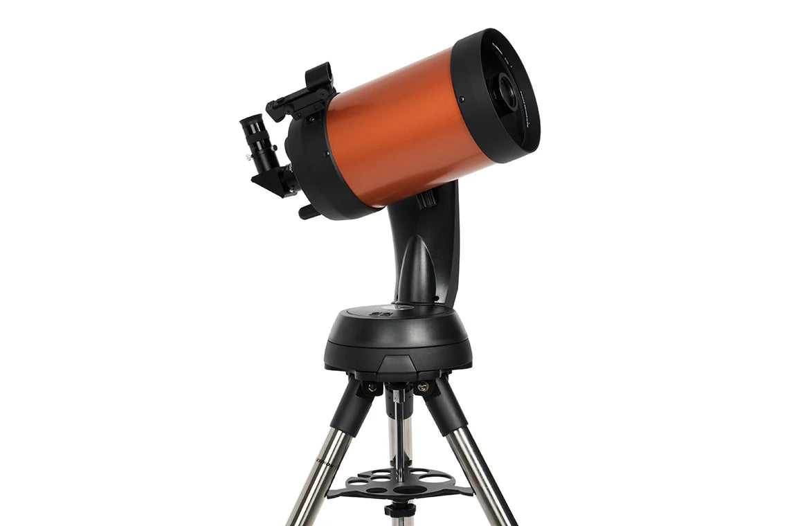  A Celestron NexStar 6SE telescope with an orange cylindrical tube mounted on a black computerized base and a silver tripod. The telescope is angled slightly upward for observation.
