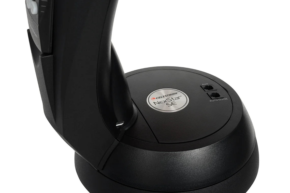 A close-up view of the base of a Celestron NexStar 6SE telescope. The base features the Celestron branding and model name "NexStar SE" on a circular metal plate.