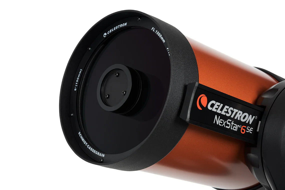 A close-up view of the front end of a Celestron NexStar 6SE telescope, showing the large aperture and lens. The orange cylindrical tube is mounted on a black bracket with the Celestron branding and model name "NexStar 6SE" prominently displayed