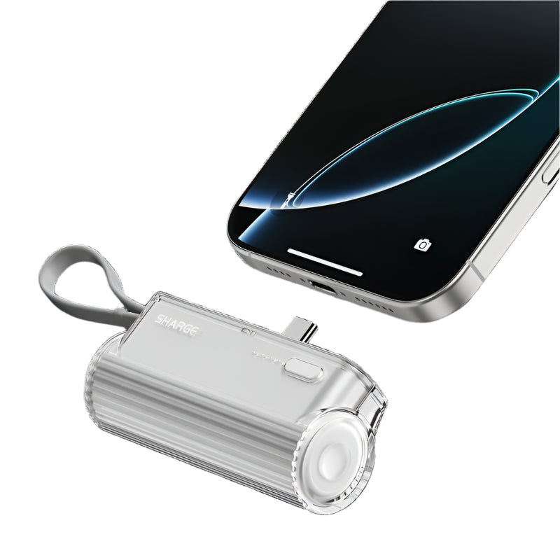 A compact, transparent portable device with a cylindrical design, featuring a ribbed texture, a speaker-like grill on one end, a power button, and LED indicators. It includes a top-mounted knob and a wrist strap for easy handling. Positioned next to a modern smartphone with a sleek, minimalist design and a glowing screen. The device appears designed for connectivity or audio purposes.