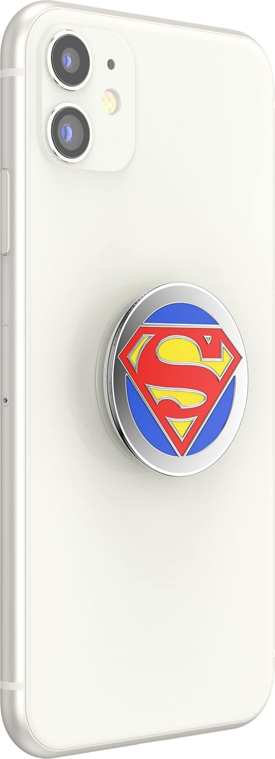  A white smartphone with a PopSockets Enamel Swappable Grip featuring the Superman logo attached to the back. The grip displays the iconic Superman "S" shield in red and yellow on a blue background, encased in a shiny metal border. The design adds a pop of color and superhero flair to the phone, providing both style and functionality with its swappable and expandable features.