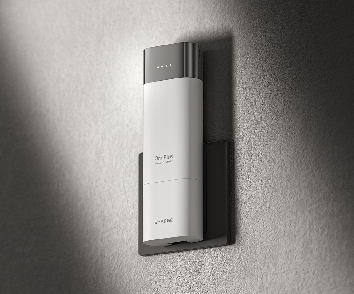 The image you uploaded shows a sleek, white charging device mounted on a wall outlet. The device is branded with "OnePlus" and "Sharge," indicating a collaboration between the two brands. The charger features a modern design with metallic accents and an LED indicator on the top to display the charging status. The overall appearance is minimalist and sophisticated, fitting well in a contemporary setting.