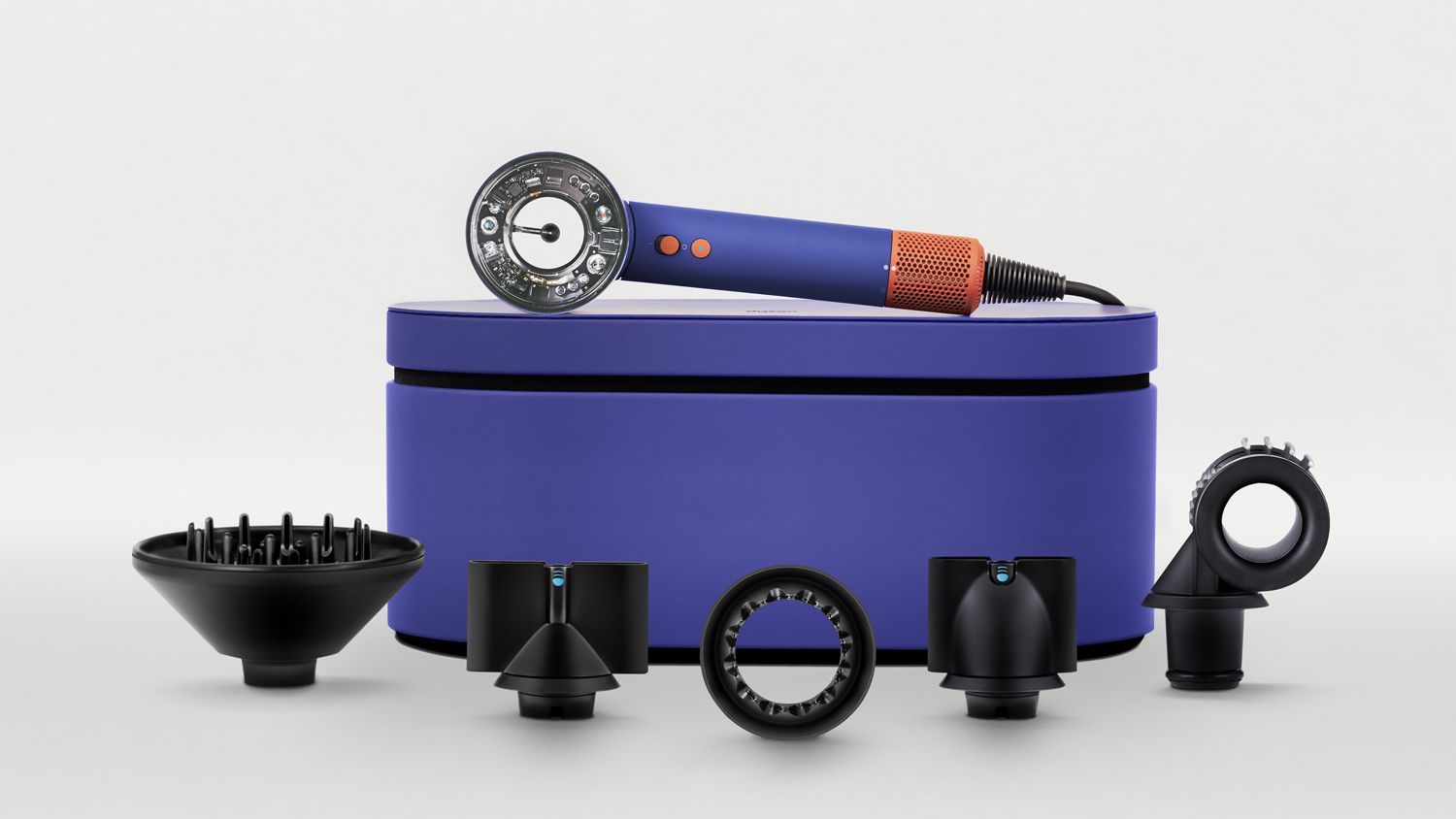 A blue hair dryer displayed with multiple black attachments and a matching storage case, showcasing various styling options and an exposed technological design at the front.