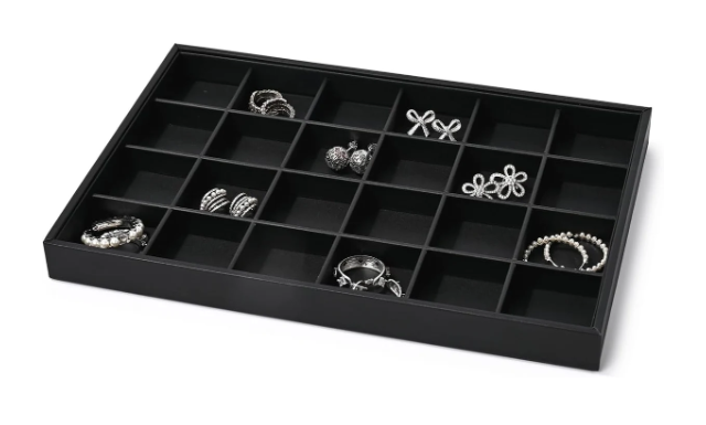 Black jewelry organizer tray with multiple compartments holding rings, earrings, and bracelets.