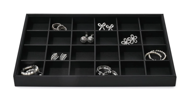 Black jewelry organizer tray with multiple compartments holding various rings, earrings, and bracelets.