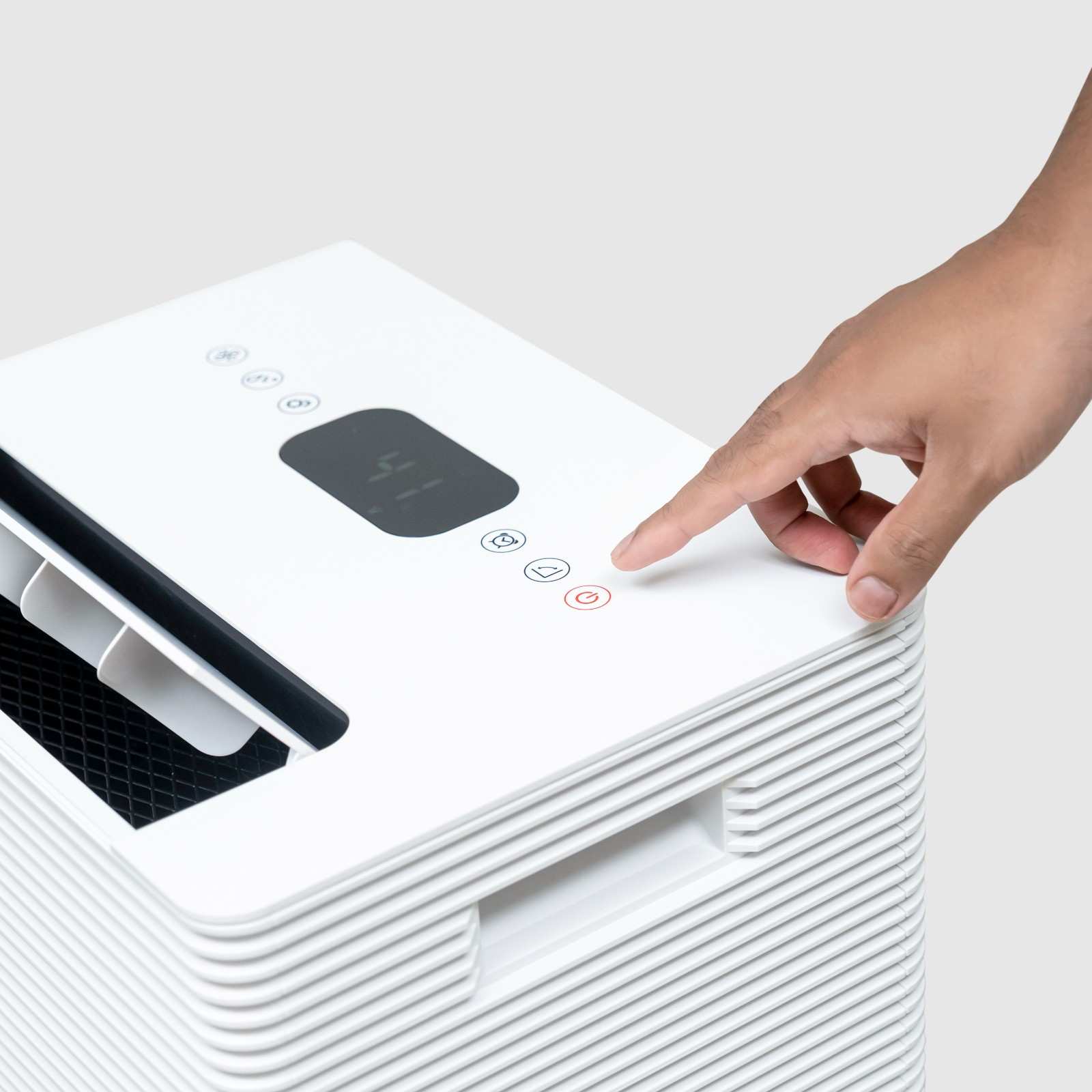 Close-up view of a person pressing the power button on the digital control panel of the White Westinghouse Dehumidifier AWHD40. The top section also features a built-in handle and air vents. The sleek white design is suitable for maintaining optimal humidity levels in residential and commercial spaces.