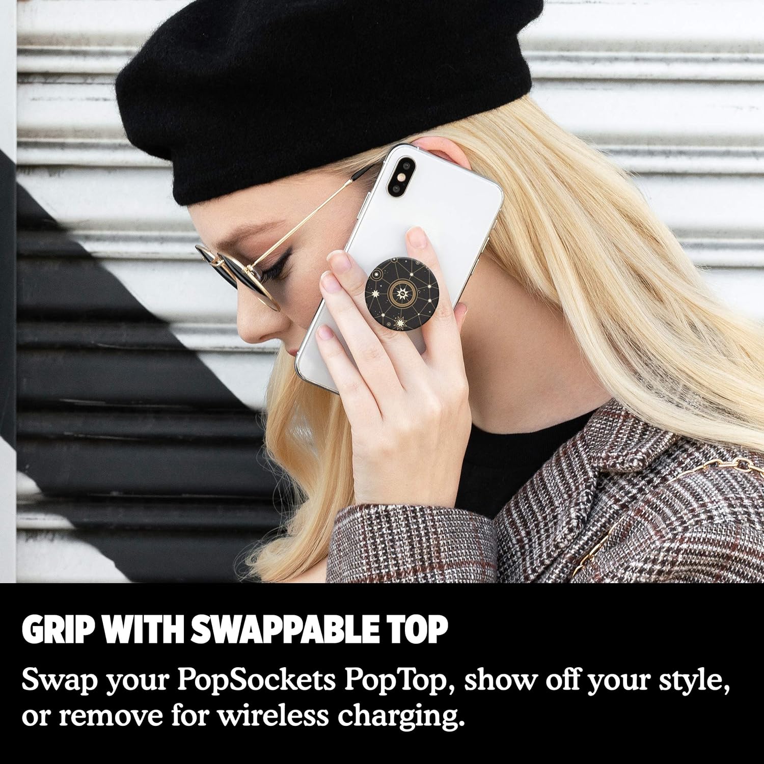 A woman wearing a black beret and sunglasses is holding a white phone with a PopSockets grip featuring a star chart design. The text below reads, "GRIP WITH SWAPPABLE TOP. Swap your PopSockets PopTop, show off your style.