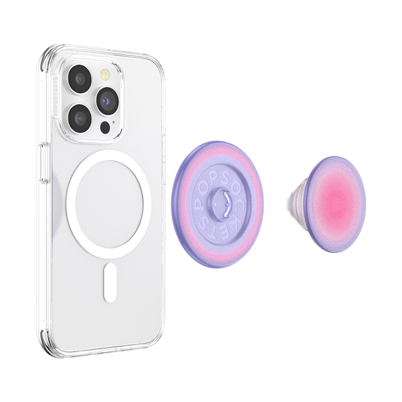 The PopGrip is separated into two parts: the round base with the PopSockets logo and the extendable grip with a gradient color pattern transitioning from pink in the center to purple on the edges. The clear case allows visibility of the phone's details and the MagSafe ring, highlighting the PopGrip's stylish and functional design.