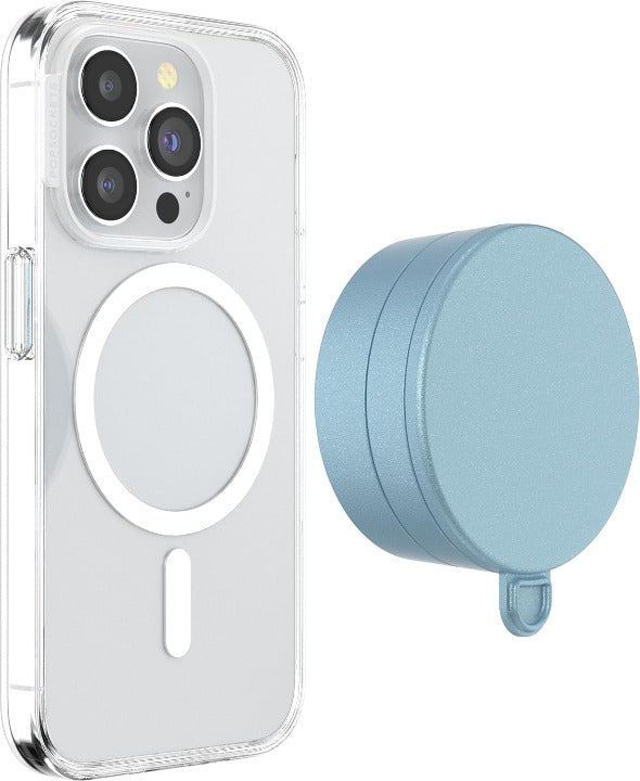 A smartphone with a clear case is shown next to a blue sigh PopSockets Suction Mount for MagSafe. The phone's back displays the MagSafe alignment ring, indicating its compatibility with MagSafe accessories. The mount is positioned beside the phone, highlighting its circular design and soft blue color. The clear case allows visibility of the phone's details and the MagSafe ring, emphasizing the mount's functional and stylish design.