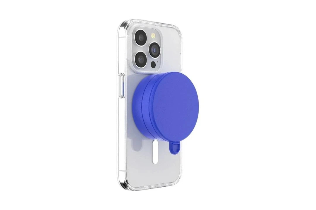 A smartphone with a clear case is shown with a cobalt blue PopSockets Suction Mount for MagSafe attached to its back. The mount is securely positioned in the center of the phone's back, demonstrating its compatibility and ease of use with MagSafe technology. The phone's camera lenses are visible at the top, highlighting the mount's unobtrusive and vibrant design.