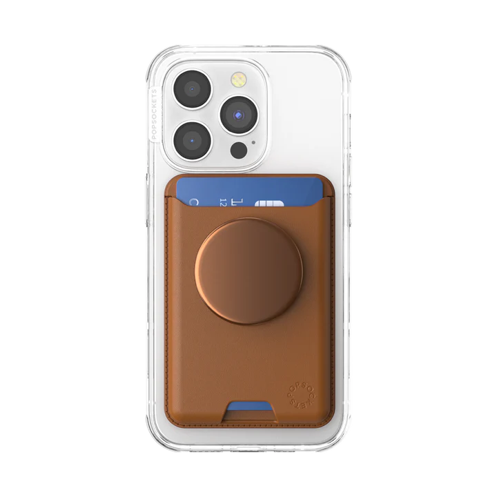  A PopSockets MagSafe Softgoods PopWallet in Cognac attached to the back of a clear iPhone case. The wallet holds a blue card, partially visible at the top, and features a cognac-colored circular PopSocket in the center. The clear iPhone case allows the design of the phone and wallet to be fully visible.