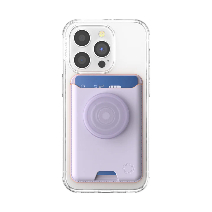 A close-up view of the back of an iPhone with a clear case. Attached to the back is a PopSockets MagSafe Softgoods PopWallet in Pale Lavender color. The wallet is holding a blue credit card and features a PopSocket in the same pale lavender shade. The PopSocket has a circular design, and the wallet's stitching adds a decorative touch. The PopSockets logo is subtly embossed near the bottom right corner of the wallet.