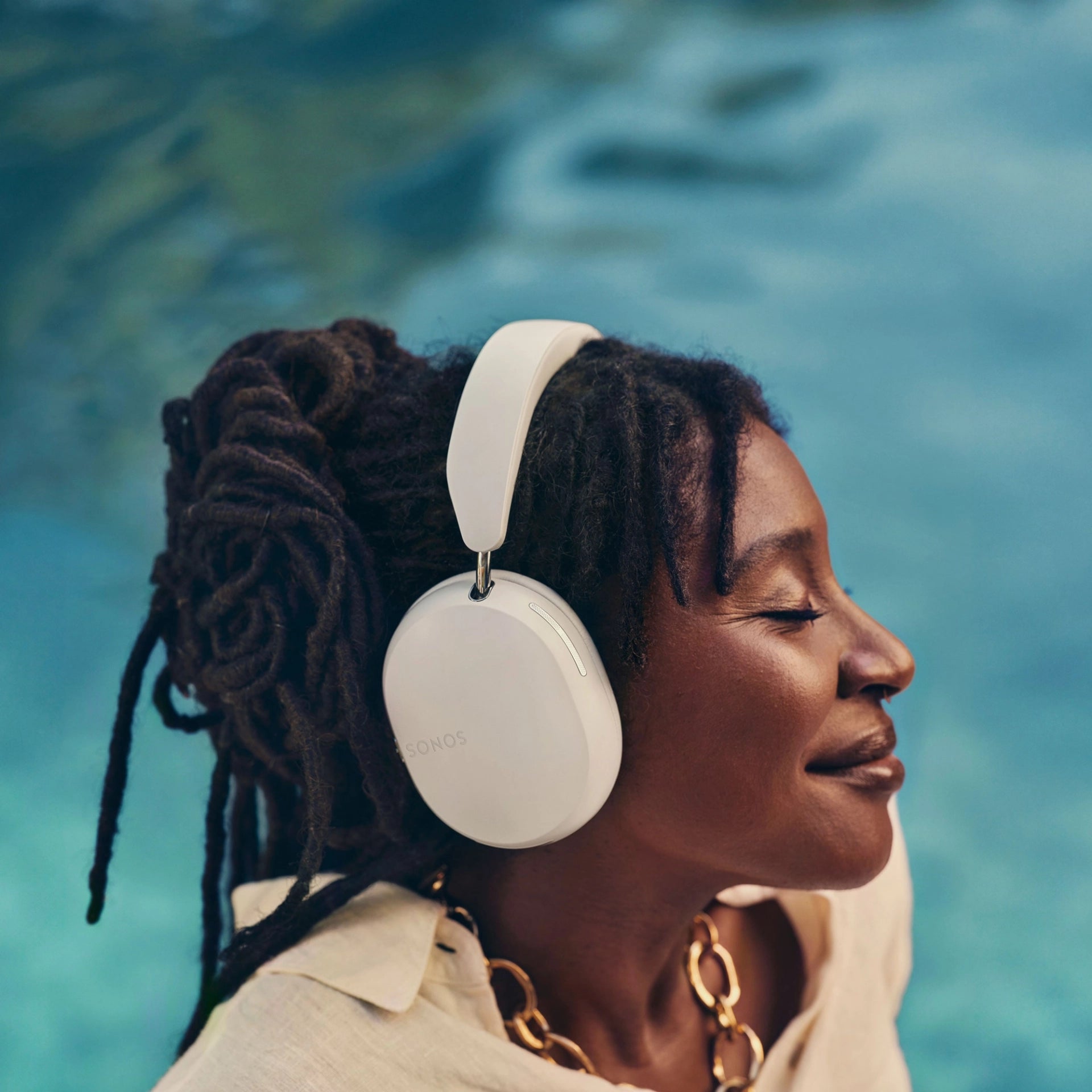 Woman enjoying music while wearing white Sonos wireless over-ear headphones, highlighting comfort and sleek design.