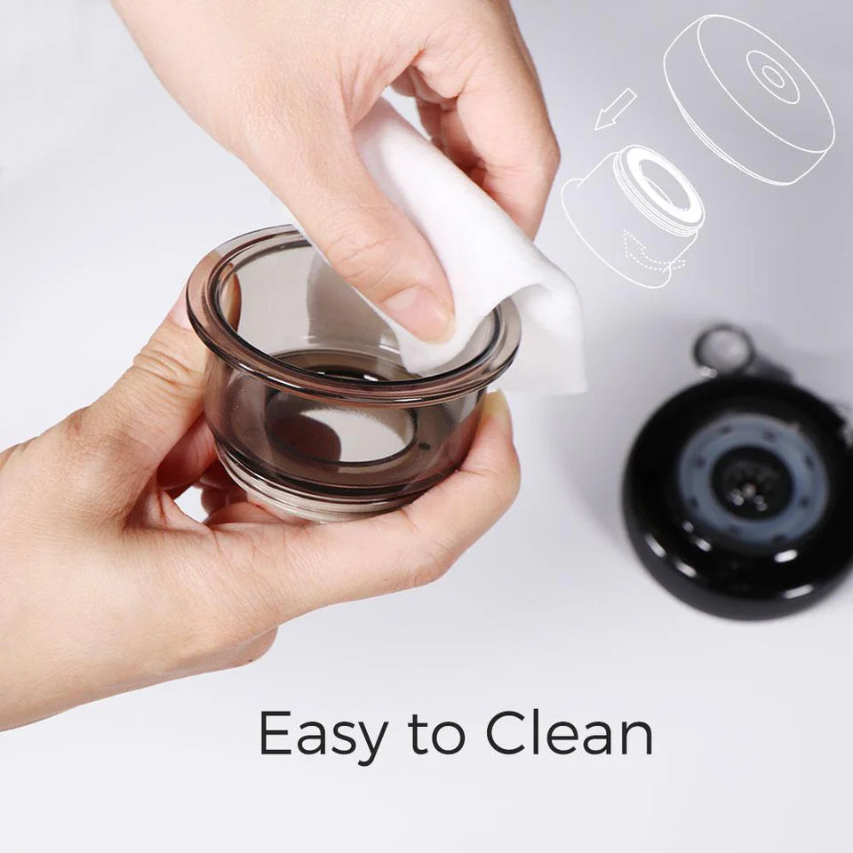 Close-up of hands cleaning a transparent suction cup from a cupping therapy device with a soft cloth. The detachable design allows for easy maintenance, as indicated by the text "Easy to Clean." A visual illustration in the background shows the cup's attachment mechanism, with the device unit placed nearby.