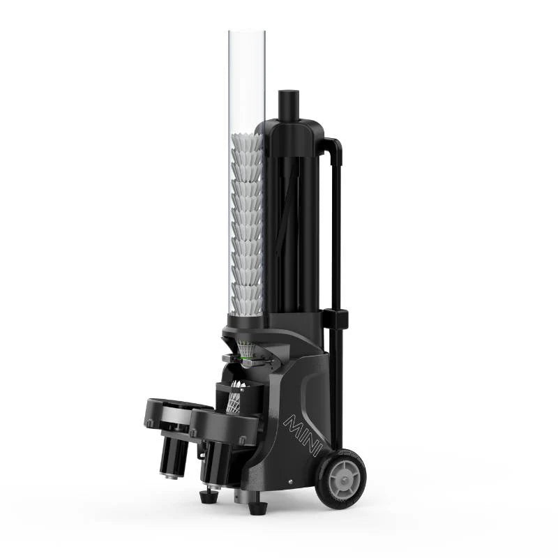 This image shows a sleek, modern badminton shuttlecock feeder machine labeled "MINI." The machine is compact and features a tall, transparent tube holding shuttlecocks, with a robust base and wheels for easy mobility. The design emphasizes functionality and efficient delivery of shuttlecocks for training or recreational use, and it appears durable and well-built for consistent performance.