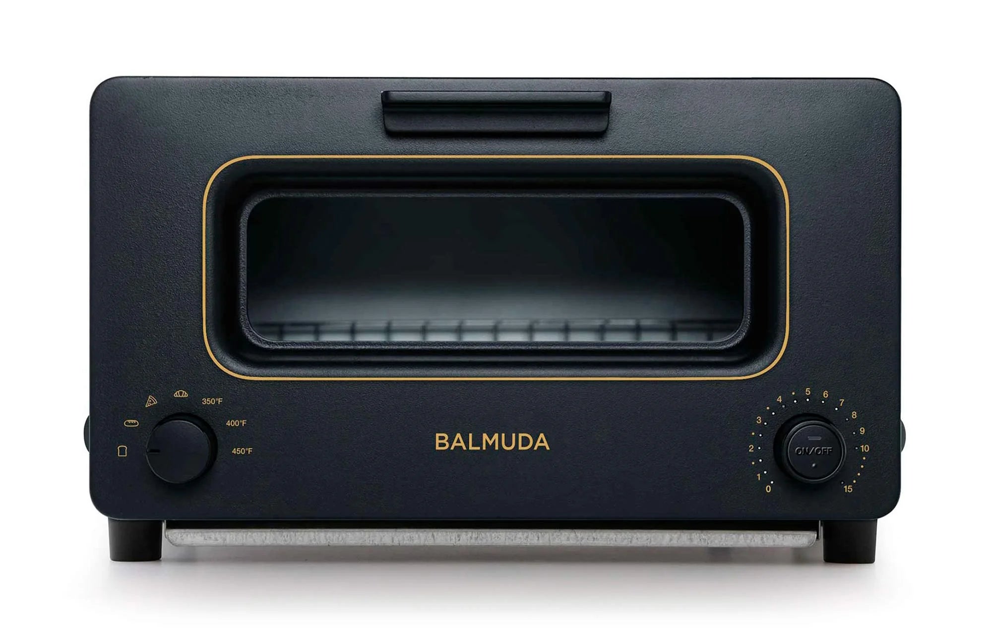  The image shows a front view of a Balmuda toaster in a matte black finish with gold accents. The toaster features a large rectangular viewing window centered on the front, bordered by a gold trim. Below the window, the brand name "BALMUDA" is prominently displayed in gold lettering