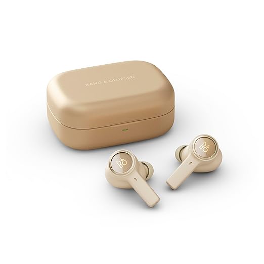 The image shows a set of beige Bang & Olufsen wireless earbuds with a matching charging case. The earbuds have a sleek, minimalist design with the "B&O" logo on each earpiece. The case features a compact, smooth finish with the Bang & Olufsen branding on the top.