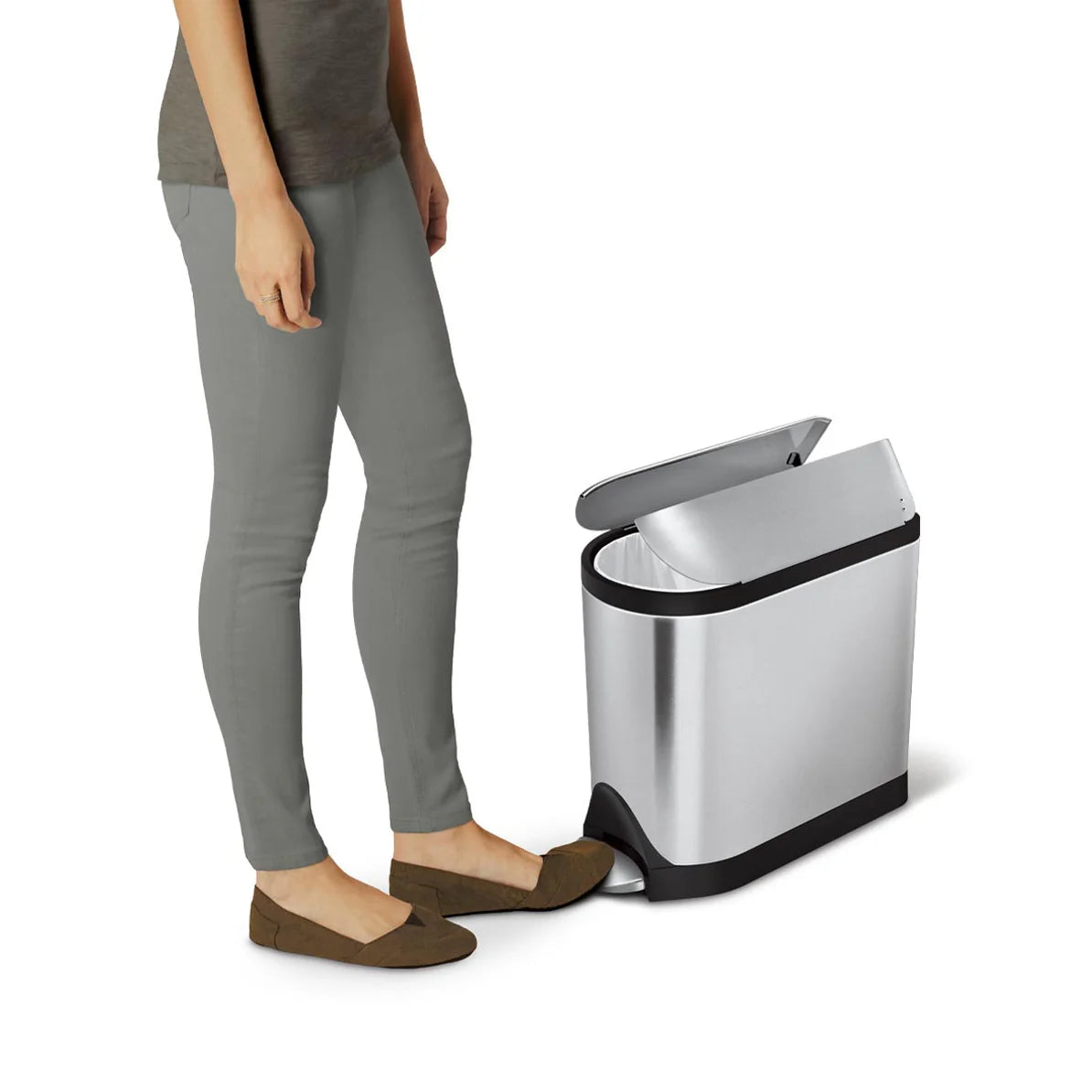 The image features a person using a stainless steel trash can with a foot pedal mechanism. The trash can lid is open, demonstrating its hands-free operation. The sleek, modern design of the trash can complements its functionality, making it an ideal choice for efficient waste management in any room. The compact size is perfect for fitting in tight spaces, while the stainless steel finish adds a touch of elegance.