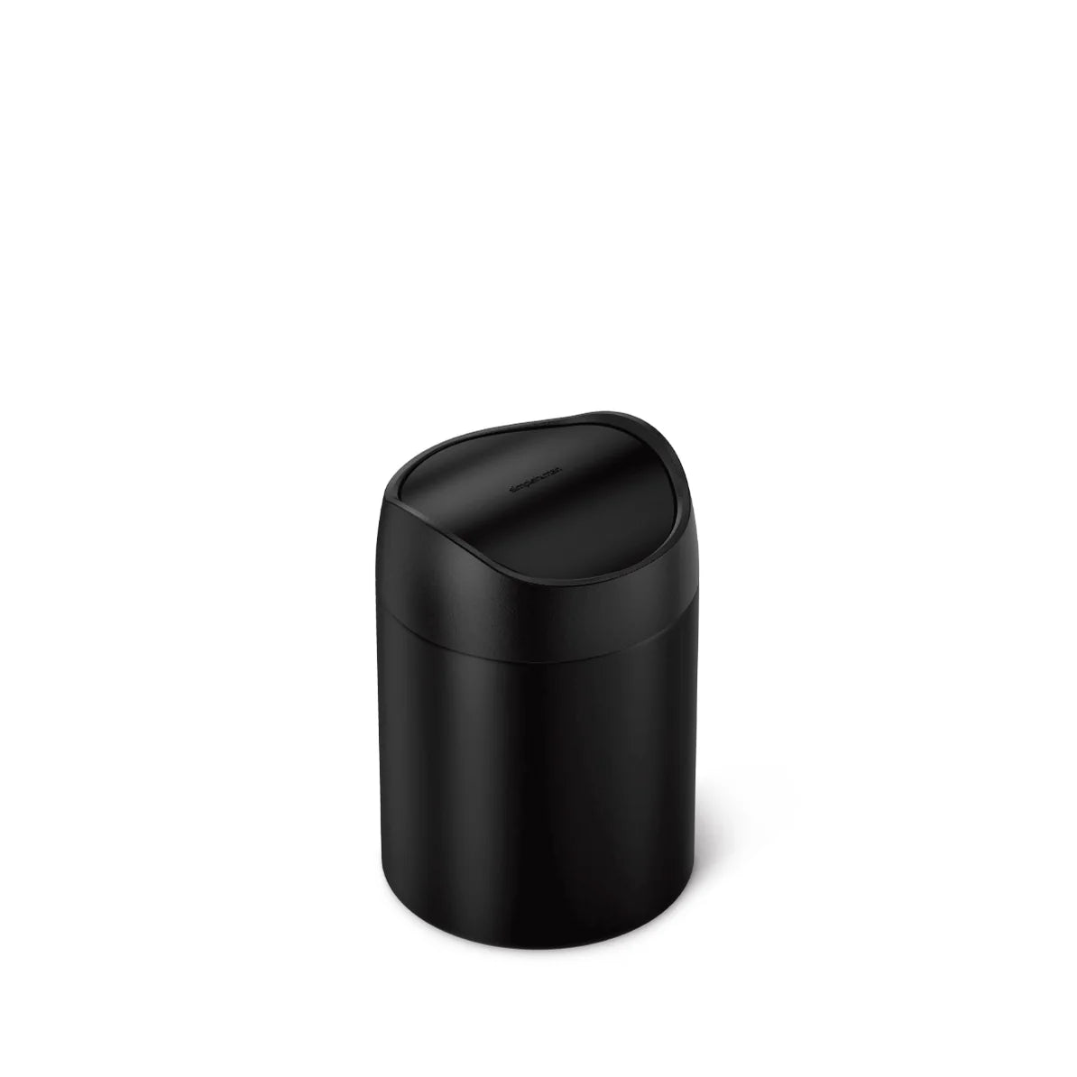 The image shows a Simplehuman mini round trash can with a swing lid, featuring an all-black finish. The trash can is compact and cylindrical, making it suitable for use on a bathroom countertop, vanity, or desk. The swing lid is designed to open and close easily, maintaining a clean and minimalist appearance when closed. The matte black finish gives the trash can a modern and sleek look, making it a stylish addition to any space. This design is both functional and aesthetically pleasing, ideal for those who