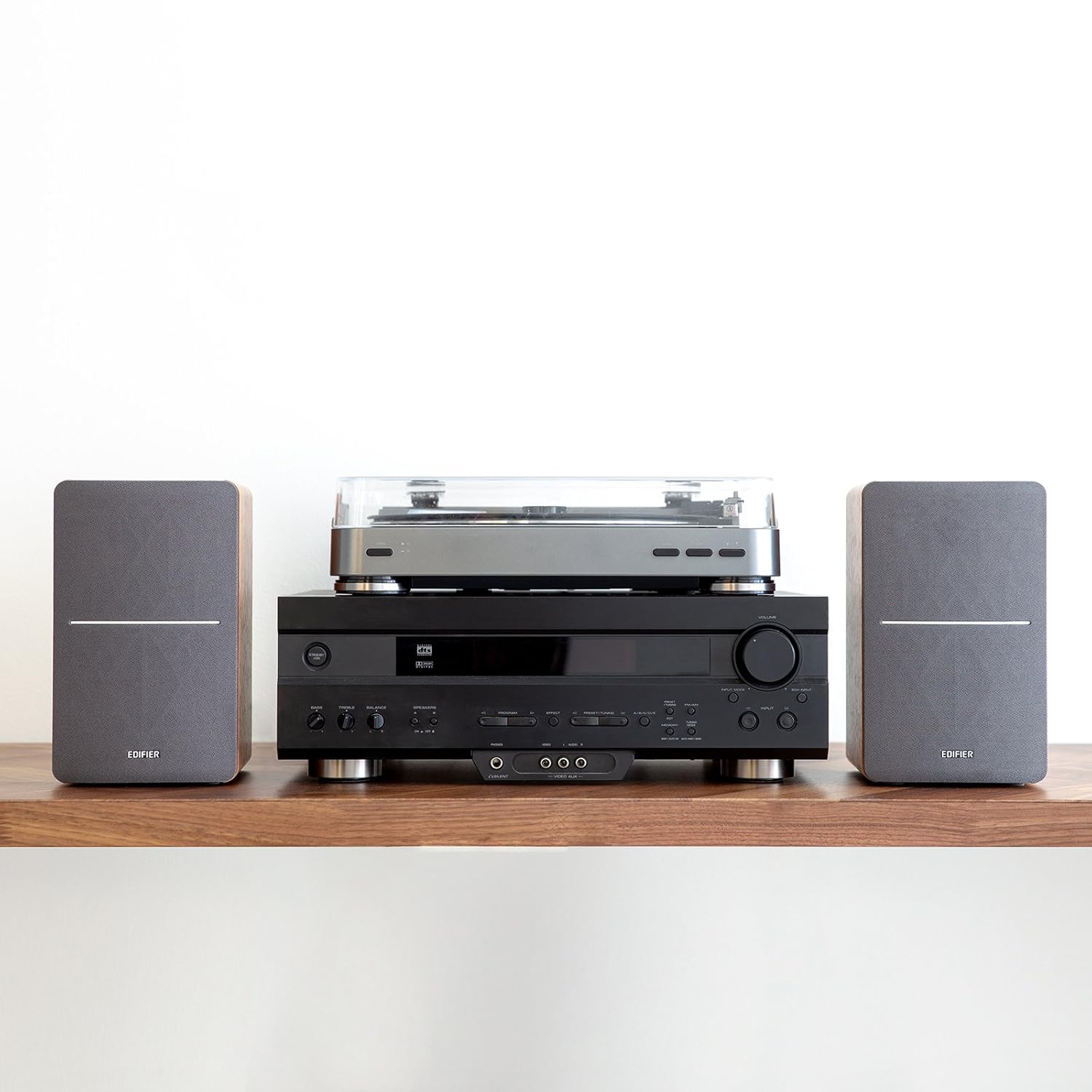 This image features a modern home audio setup, including a turntable placed on top of a black stereo receiver. On either side, two compact wooden-finish speakers complement the setup, combining functionality with aesthetic appeal. Perfect for vinyl and audio enthusiasts seeking a sleek and stylish sound system. Let me know if you need more details!