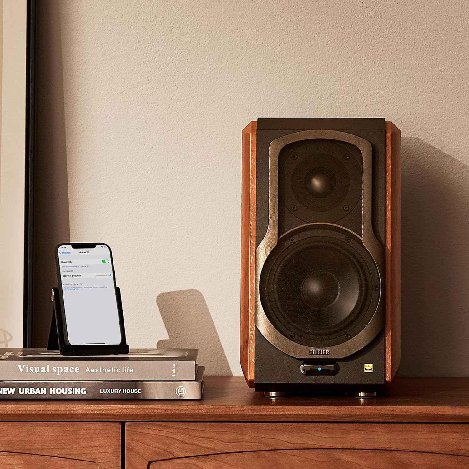 Edifier speaker with a classic wood finish, placed on a stylish desk next to books and a smartphone connected via Bluetooth, creating a sophisticated audio setup for any modern space.