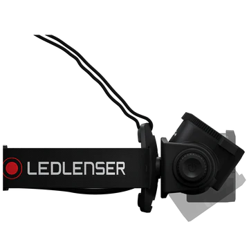 A side view of a black LED Lenser headlamp with an adjustable strap. The LED Lenser logo is prominently displayed on the strap. The headlamp features an adjustable angle mechanism, allowing the user to direct the light as needed. The background is white, emphasizing the headlamp's design and features.