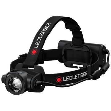  A black LED Lenser headlamp with an adjustable strap, shown at an angle. The LED Lenser logo is prominently displayed on the strap. The headlamp features a central light that is adjustable for focus and direction, with a battery pack at the back of the strap. The background is white, emphasizing the headlamp's design and components.