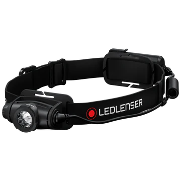  A black LED Lenser headlamp with an adjustable strap is shown at an angle. The headlamp features a prominent central light, an adjustable focus ring, and a battery pack attached to the back of the strap. The LED Lenser logo is visible on the strap. The background is white, emphasizing the headlamp's design and details.