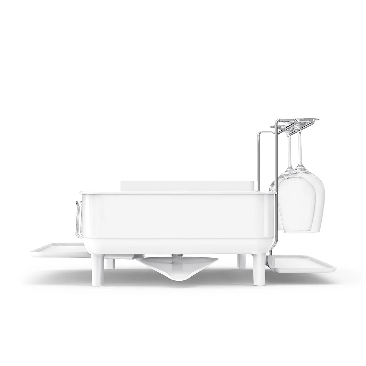 The image displays a side view of a white dish drying rack, which is elevated on legs for efficient water drainage. The rack features an integrated glass holder designed to secure delicate stemware, ensuring safe drying. Additionally, there are side trays that can be extended for extra drying space. The overall design is clean and modern, perfect for enhancing the functionality and aesthetics of a kitchen countertop.