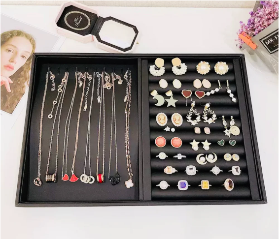 Black jewelry organizer tray displaying a collection of necklaces, earrings, and rings.