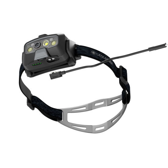 Compact LED Lenser headlamp with a secure, adjustable strap and detachable power cable. Designed for hands-free illumination during outdoor activities, featuring multiple LED lights for versatile brightness settings and a comfortable fit. The device is ideal for nighttime adventures, work, or emergencies.