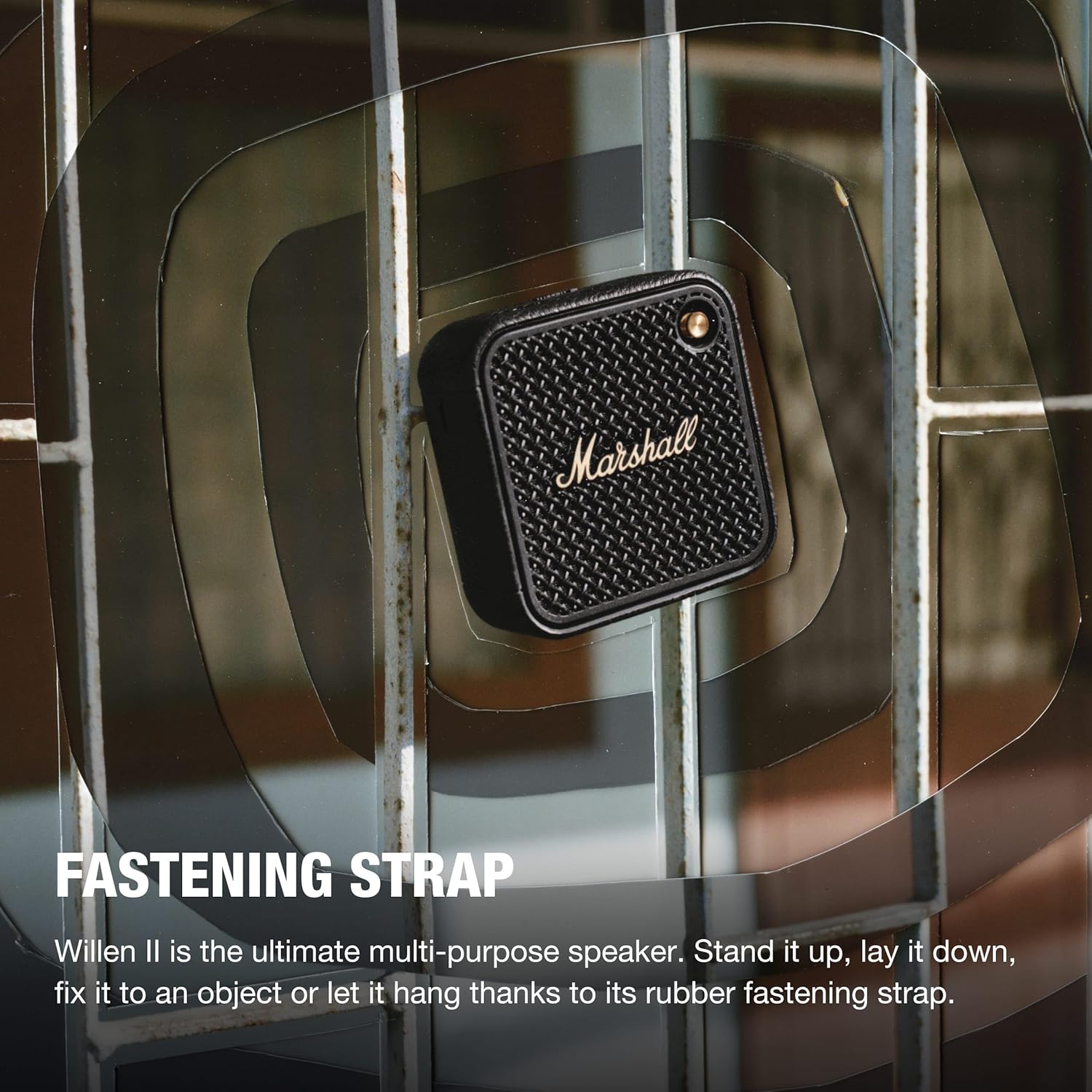 Marshall Willen II speaker attached to a metal surface using its rubber fastening strap, showcasing its versatile mounting capability for portable use.