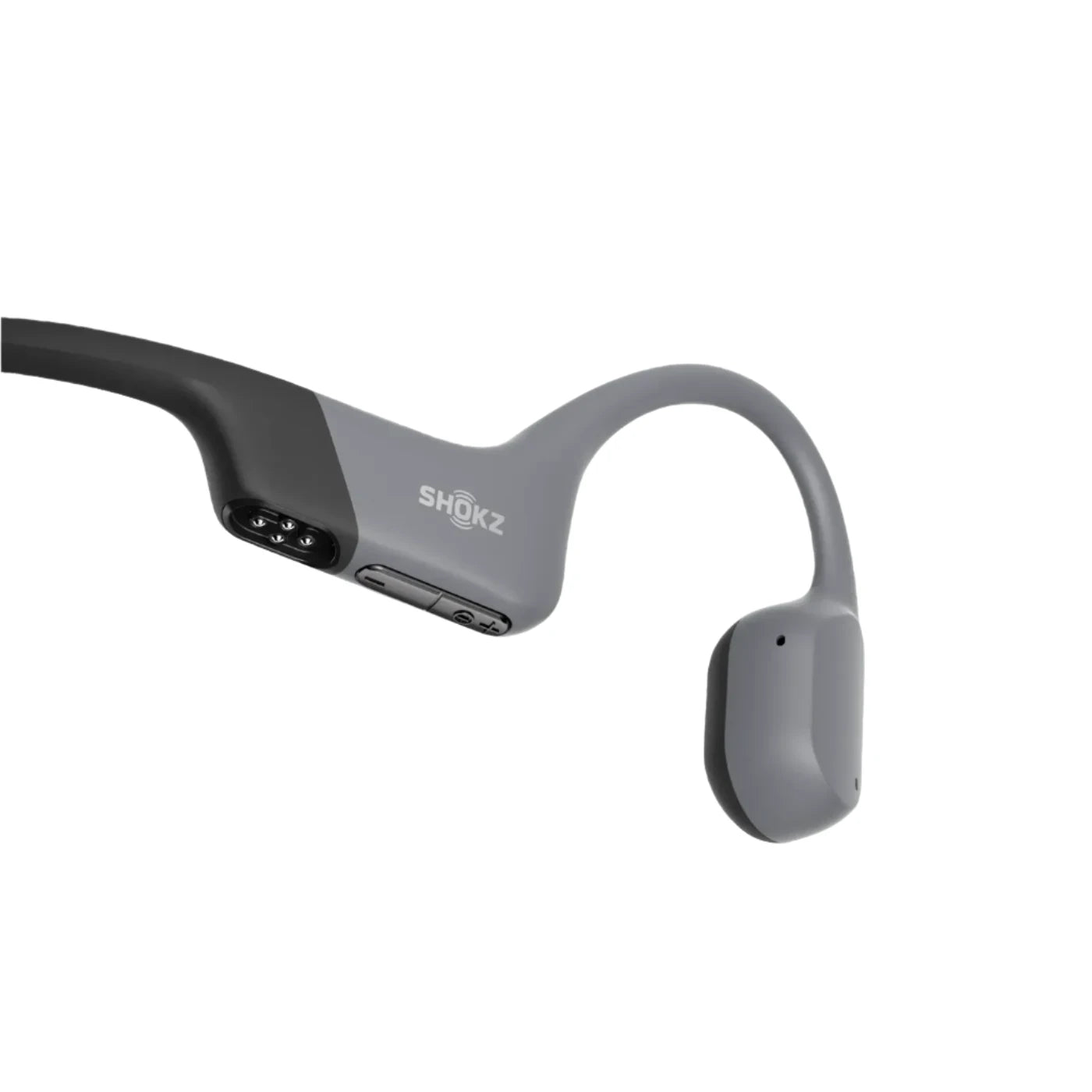 Close-up of Shokz bone conduction headphones in grey, featuring control buttons and magnetic charging port, designed for water-resistant performance during sports and swimming activities.