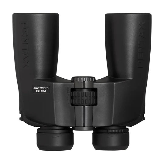 A top-down view of Pentax S-Series WP binoculars showcasing the central focusing wheel and the bridge connecting the two barrels. The binoculars have a matte black finish, with the Pentax branding visible on the outer side of both barrels. The eyepieces are capped and designed for comfortable use. The design is sturdy and ergonomic, emphasizing ease of handling and durability.