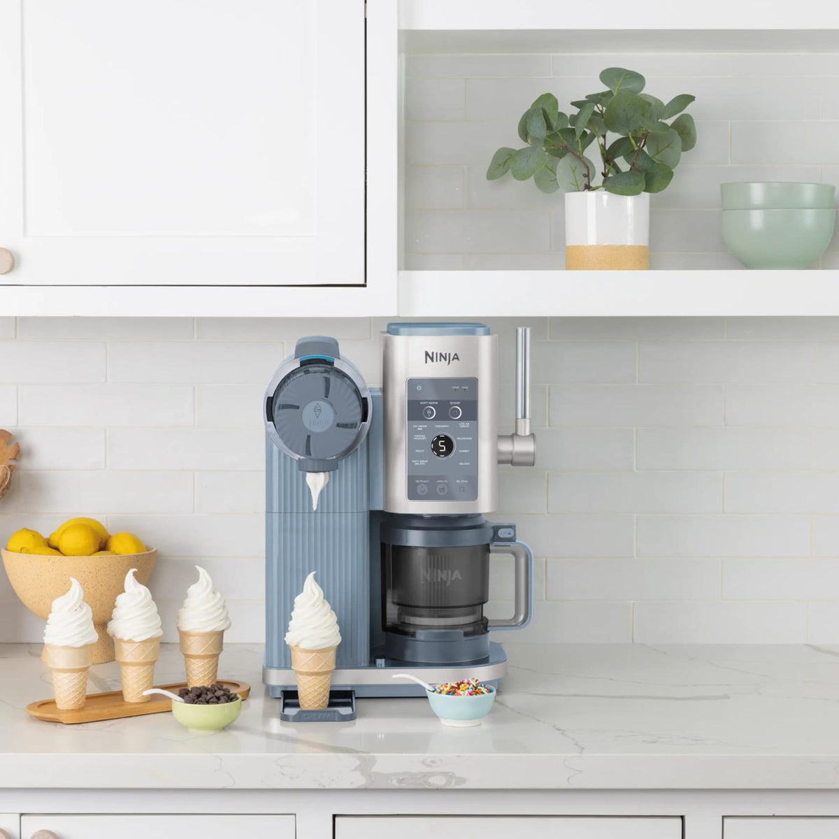 Ninja CREAMi Scoop & Swirl NC702EU on a kitchen counter with soft serve cones and toppings