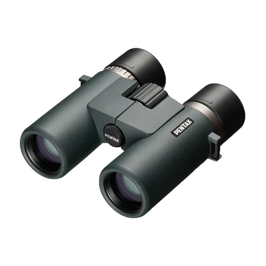 A pair of Ricoh Pentax AD 7x32 ED binoculars with a sleek, ergonomic design. The binoculars feature large objective lenses with a greenish tint and a durable body with a matte finish. The Pentax branding is prominently displayed on the side of the right barrel. The central focusing wheel is positioned between the two barrels for easy adjustment. The binoculars are designed for a comfortable grip and handling, emphasizing high-quality optics and durability.