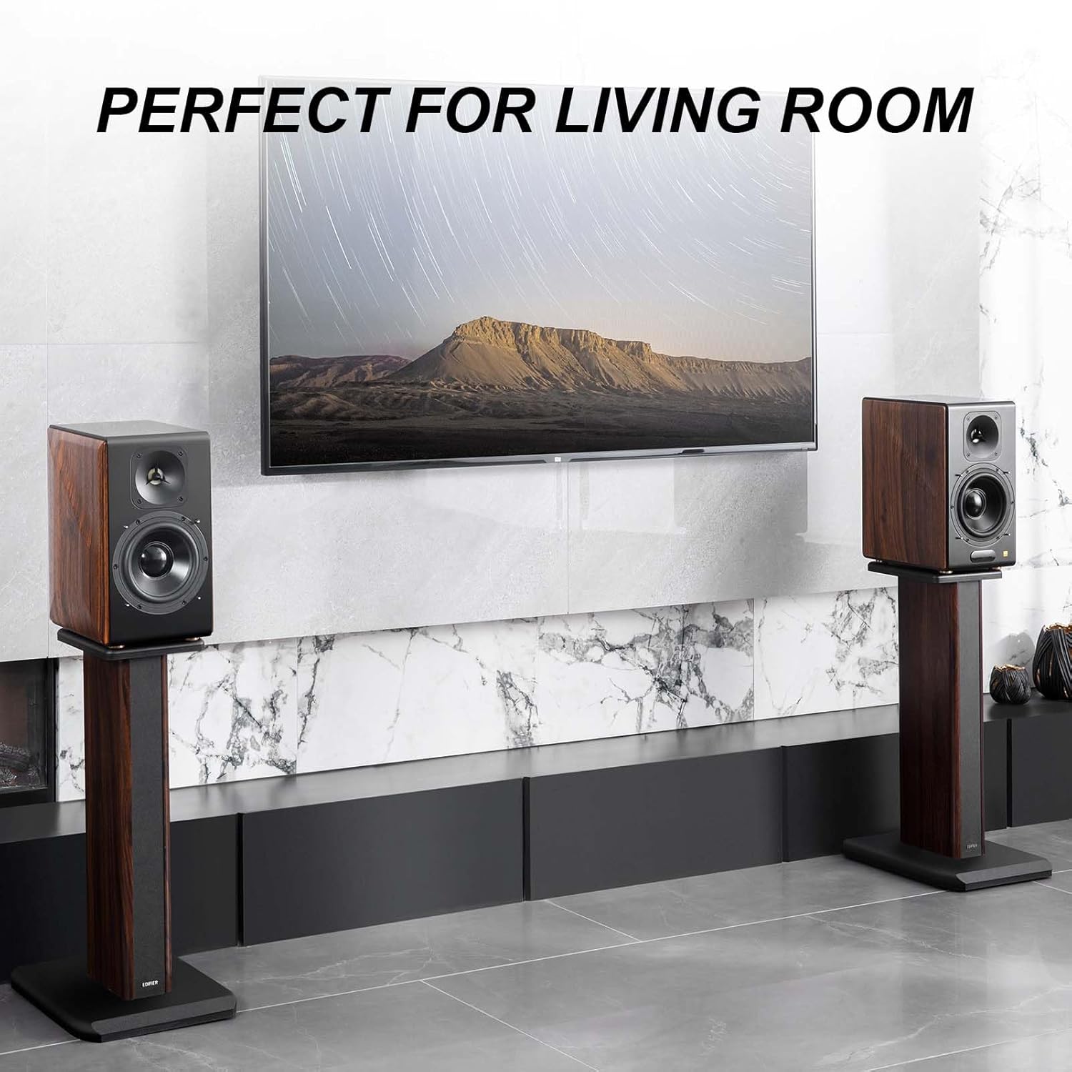 A modern living room setup featuring a wall-mounted TV displaying a scenic landscape, accompanied by two high-end wooden bookshelf speakers on matching stands. The sleek marble wall and minimalist decor enhance the elegant aesthetic, with the text "PERFECT FOR LIVING ROOM" highlighting the suitability of this audio-visual setup for home entertainment.