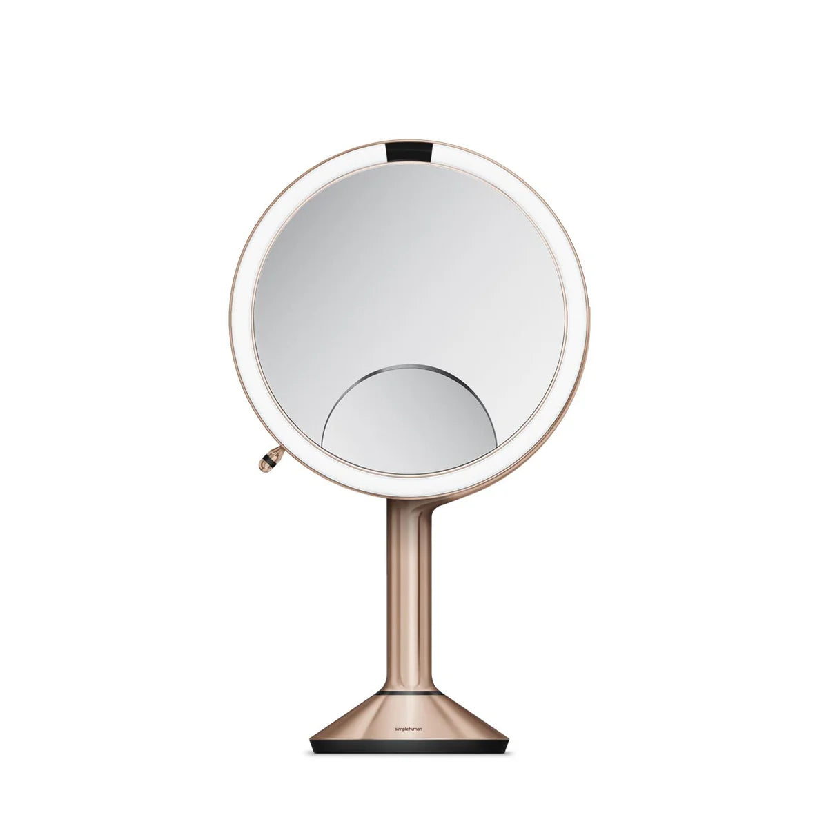 This image shows a sleek and elegant makeup mirror, likely from the Simplehuman brand, known for its high-quality home and lifestyle products. The mirror features a round, well-lit design with an LED light ring around the edge, which provides even and bright illumination for clear visibility while applying makeup or performing skincare routines.  The mirror is mounted on a slim, metallic stand with a rose gold finish, adding a touch of luxury to the design. The base is sturdy, ensuring stability on any surf