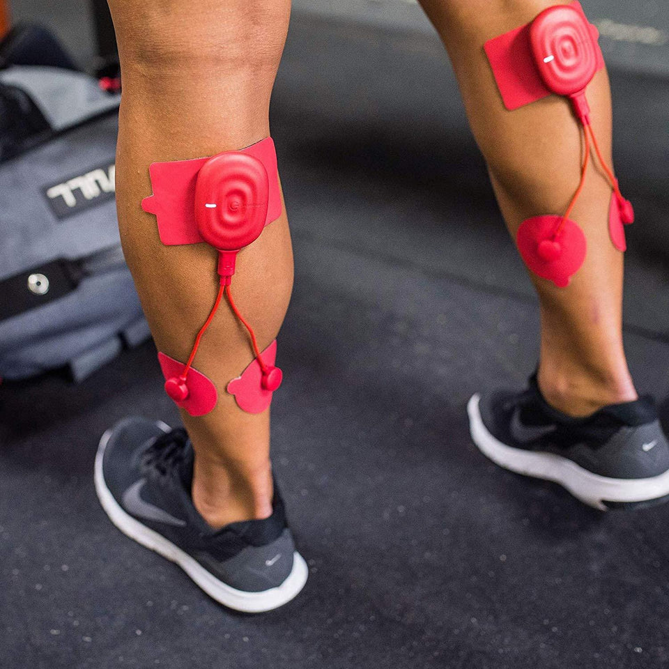 A person wearing red muscle stimulation pads on their calves, connected to wires for targeted recovery and performance enhancement during a fitness session.