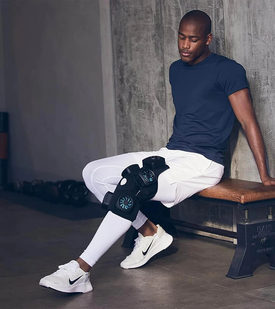 A man sitting on a bench wearing the Therabody RecoveryTherm device on his knee, showcasing its ergonomic design and effectiveness for muscle recovery and pain relief during post-workout relaxation.