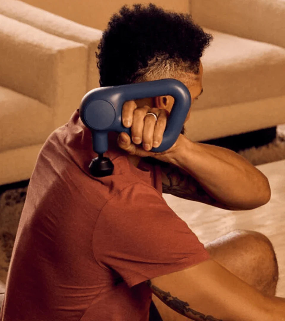 A man using a blue Theragun massage device on his shoulder, highlighting its ergonomic handle and effectiveness for targeted muscle relief and recovery.