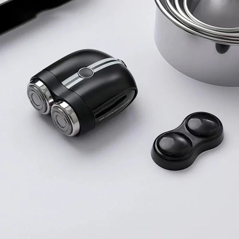 This image displays a compact, black, dual-head electric shaver with a sleek design, featuring white racing stripes down the middle, reminiscent of a sporty aesthetic. The shaver is accompanied by a matching black protective cap for the shaving heads, emphasizing its portability and convenience for travel. The stainless steel elements and smooth, curved lines of the shaver give it a premium look. The overall presentation suggests that this is a well-crafted, stylish grooming tool, suitable for users who app