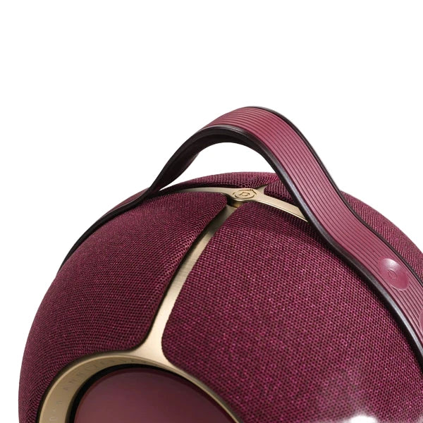 Close-up of a maroon suitcase with gold accents on a light gray background