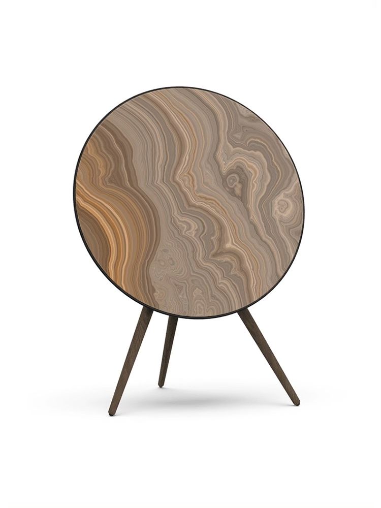 Bang & Olufsen speaker with a unique skin cover featuring a circular design with a brown, wood-like pattern and standing on a tripod