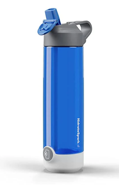 The image displays a blue HidrateSpark water bottle with a flip-top lid. The bottle has a sleek, cylindrical design with a grey lid that includes a spout for easy drinking. The brand name "HidrateSpark" is visible along the side of the bottle near the bottom. The base of the bottle appears to feature a smart sensor that tracks water intake. This design highlights both functionality and style, offering users a tech-integrated way to monitor hydration throughout the day.