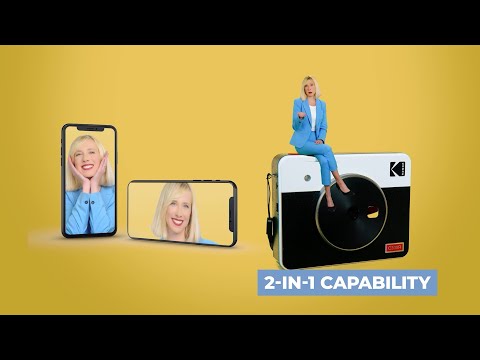 A promotional thumbnail for the Kodak Photo Printer, highlighting its **2-in-1 capability** as both an instant camera and a Bluetooth printer, featuring a woman in a blue suit sitting on the device with images displayed on smartphones against a yellow background.